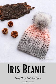 a crocheted hat with a pom - pom sits next to some pine cones