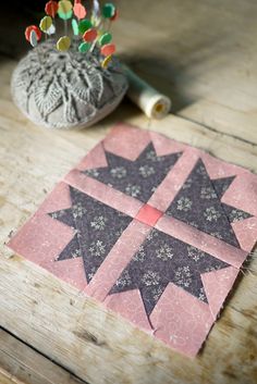 a close up of a piece of fabric on a wooden table with a pin cushion