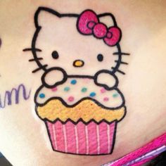 a hello kitty tattoo on the side of a woman's stomach with a cupcake