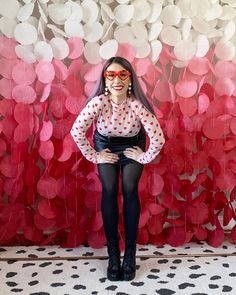 a woman standing in front of a red and white wall with hearts on it's side