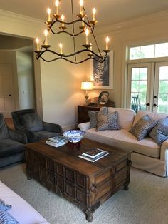 a living room filled with furniture and a chandelier hanging over the top of it