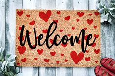 a welcome mat with hearts on it next to red shoes and succulents