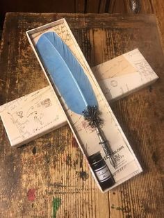 a blue feather quill sitting in a box on top of a wooden table