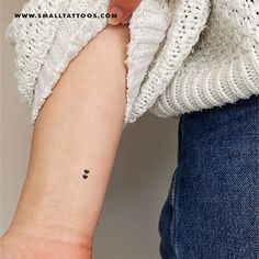 a small black dot tattoo on the left inner forearm and wrist, with an arrow in the middle