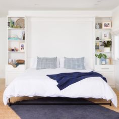 a bed with white sheets and blue pillows