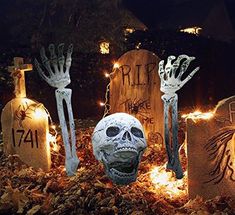 halloween decorations with lighted hands and skulls on the ground in front of tombstones at night