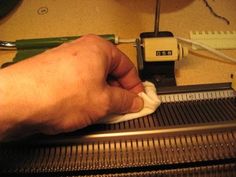 a person is using a sewing machine to sew something on the table with their hand