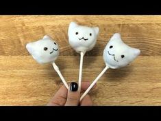 someone holding four marshmallows with faces on them