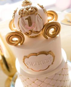 a three tiered cake with gold decorations on it's sides and the number one on top