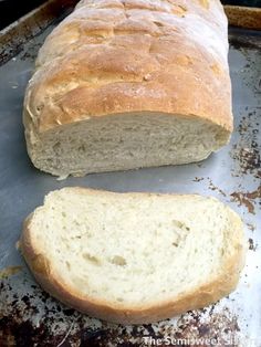 a loaf of bread sitting on top of a metal pan next to a piece of bread