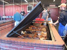 people are standing around an outdoor bbq with food on it