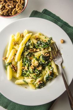 pasta with spinach and walnuts in a white bowl on a green place mat