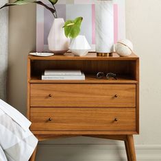 a wooden dresser with two white vases on top and one green plant in the middle