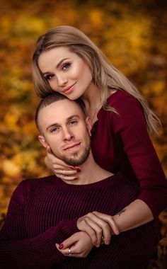 a man and woman posing for a photo in the fall leaves with their arms around each other