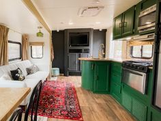 the interior of an rv with green cabinets and rugs on the wood flooring