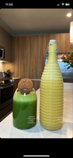 two jars with green and yellow liquid on a counter top in a kitchen, one has a corked lid