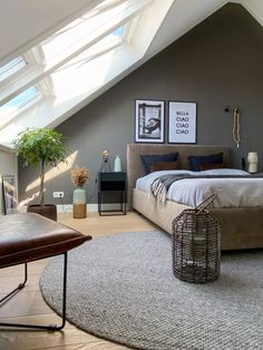 a large bed sitting under a skylight in a bedroom next to a table and chair