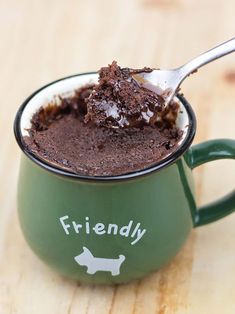 a spoon full of chocolate pudding in a green mug with the word friendly on it