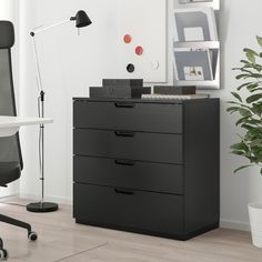 a black filing cabinet in an office with a desk lamp and potted plant next to it