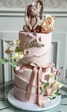 a pink cake decorated with flowers and a bunny on top