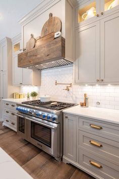 a stove top oven sitting inside of a kitchen next to white cupboards and drawers