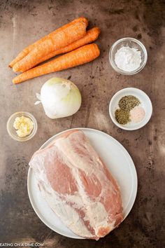 raw meat, carrots, garlic and seasoning on a plate with other ingredients