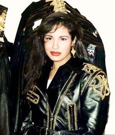 a woman with long hair wearing a black leather jacket and gold trimming on her head