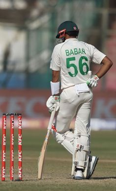 a man standing next to a cricket ball on top of a field