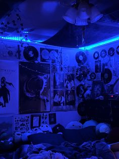 a bedroom with blue lights and posters on the wall above it, along with other items