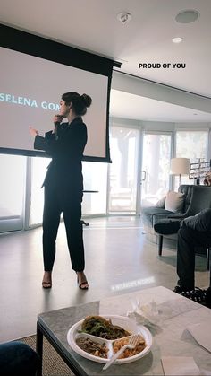 a woman standing in front of a projector screen giving a presentation