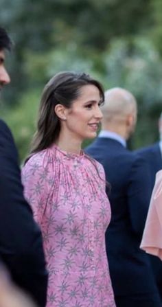 a woman in a pink dress standing next to other people