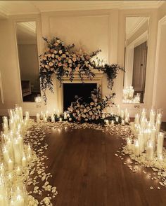 a room filled with lots of candles and flowers on the floor next to a fire place