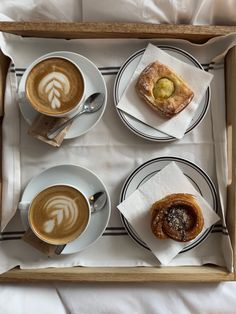 three cups of coffee and two pastries on a tray