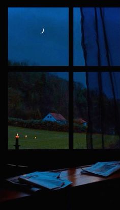 an open window with a view of a house and the moon in the night sky