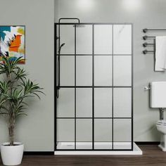 a bathroom with a shower, toilet and plant in the corner on the floor next to the bathtub