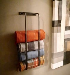 towels are hanging on the wall next to a towel rack with four folded towels in it