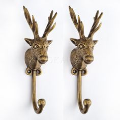 two brass deer head hooks on a white wall