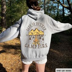 "This cozy \"Life Is Better By The Campfire\" hoodie is the perfect outfit for any camping crew or outdoorsy traveler who loves to explore nature and go on adventures. This camping hoodie features a stylish design with a campfire graphic, making it an ideal gift for any camp lover. Whether you're sitting by the fire with friends or embarking on a new outdoor adventure, this hoodie will remind you that life is always better by the campfire. ✧ SIZING ✧ ⋒ Please check our size chart before placing Cozy Sweatshirt With Kangaroo Pocket For Outdoor, Cozy Hoodie For Outdoor Activities, Cozy Long Sleeve Hoodie For Outdoor Activities, Comfortable Outdoor Fall Hoodie, Cozy Long Sleeve Hoodie For Outdoor, Cozy Outdoor Top With Drawstring Hood, Cozy Outdoor Sweatshirt With Letter Print, Cozy Fleece Hoodie For Outdoor Activities, Cozy Fleece Sweatshirt For Outdoor Activities