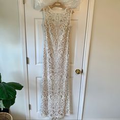 a white lace dress hanging on a door