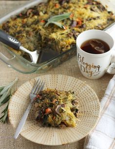 a casserole on a plate next to a cup of tea and a fork