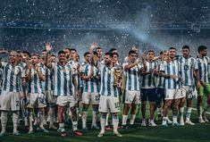 a group of men standing on top of a soccer field holding up their hands in the air