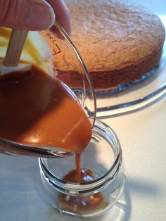 someone pouring caramel sauce on top of a cake