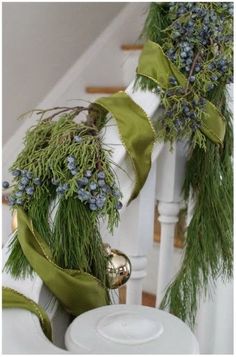 two christmas wreaths on the banister with green ribbon and bells hanging from them