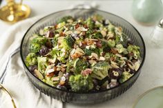 a glass bowl filled with broccoli and other food on top of a table