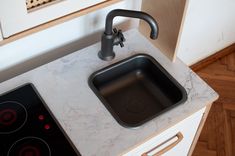 a kitchen sink with a black faucet next to it on top of a counter