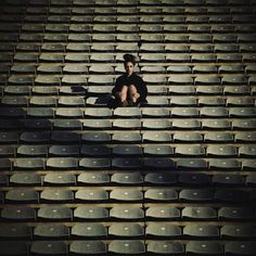 a man sitting on the bleachers in an empty stadium