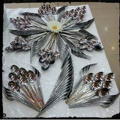 there is a table with silver and white flowers on it, along with spoons