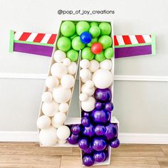 a number made out of balloons sitting on top of a floor next to a wall