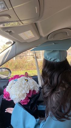 a person sitting in the back seat of a car wearing a graduation cap and gown