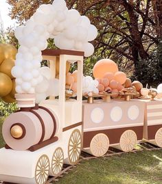 a train with balloons on the top and some decorations around it in front of trees